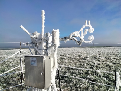 thick hoar frost on gas analyser, sonic anemomeeter and other equpment with frosty pasture in the background