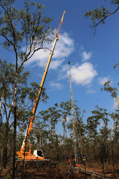 a crane lifting a section of guyed butt mast in to place